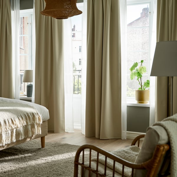 Modern bedroom with KORGMOTT curtains, rustic light, cozy bed, and window showing brick building.