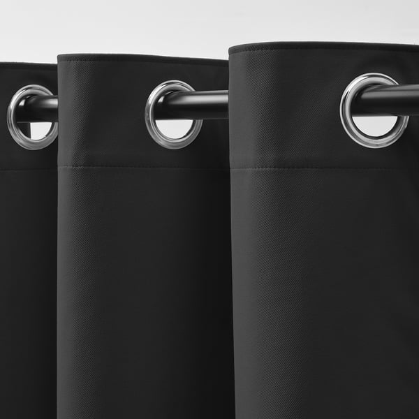 Two dark grey curtains hang from metal rods via silver eyelets, providing light blockage and sound insulation.