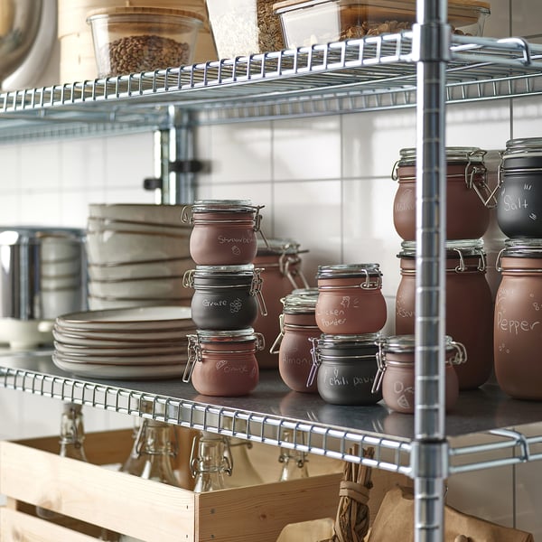 Shelves with KORKEN jars labeled with chalk for storage, showcasing organization and ease of access for kitchen items like spices and preserves.