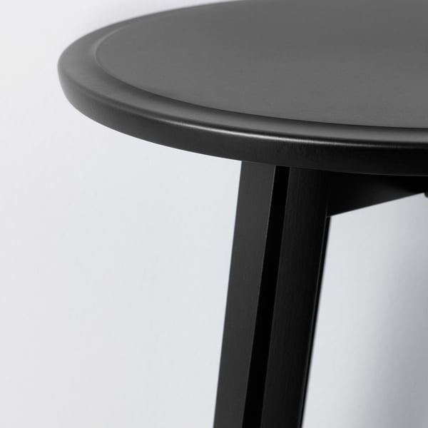 Close-up of a modern black table with smooth, rounded edges and sturdy legs. Shows high-quality design and finish.