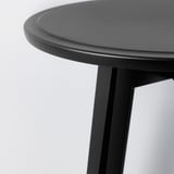 Close-up of a modern black table with smooth, rounded edges and sturdy legs. Shows high-quality design and finish.