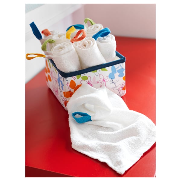 Colorful basket holds rolled white washcloths with blue bands on red surface.