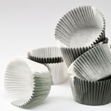 Irregular pile of folded paper baking cups, crumpled for aesthetic appeal, in neutral tones.