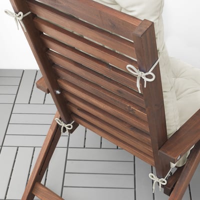 Wooden chair with beige cushion, secured by ties. Ideal for outdoor use.
