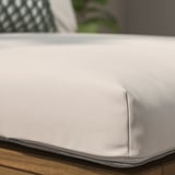 Close-up of a high-quality outdoor cushion with anti-slip dots, placed on a wooden surface.