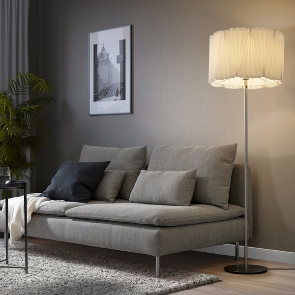 KUNGSHULT lamp brightens a room. Tall, off-white shade, soft light. Gray sofa with dark pillows and art.