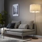 KUNGSHULT lamp brightens a room. Tall, off-white shade, soft light. Gray sofa with dark pillows and art.