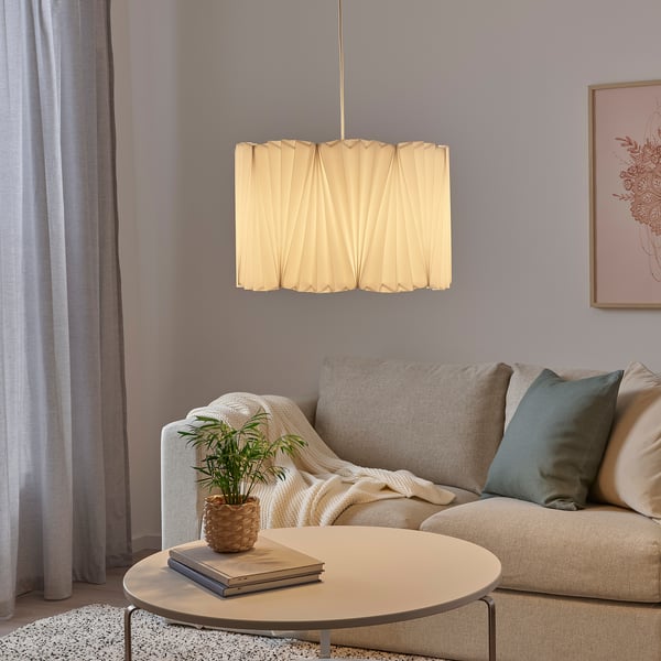 Beige pleated KUNGSHULT lamp hangs in cozy living room, complements neutral tones.