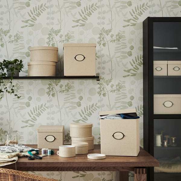 A shelves setup with KVARNVIK storage boxes in beige color, made of woven paper, holding various items.
