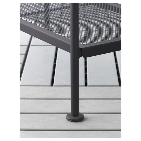 Black metal outdoor furniture with adjustable feet and perforated shelf, on grey wooden deck.