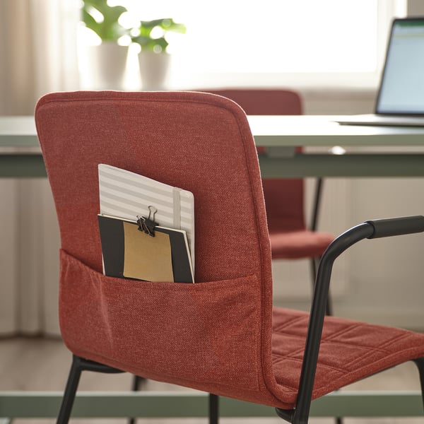 Red office chair with notebooks in back pocket.