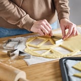 Person uses cookie cutters on dough. The cutters create shapes, ideal for baking and decorating.