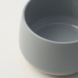 Close-up of sleek, light blue stoneware bowl, smooth texture, clean rim.