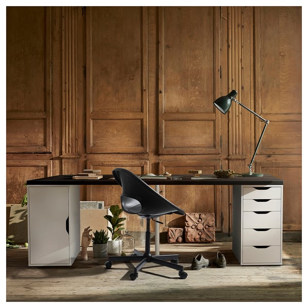 Modern home office with LAGKAPTEN desk, black chair, wooden panel walls, and adjustable lamp.
