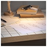 Square white desk with sketches, books, and pen. Desk has pre-drilled holes and plywood edge.
