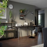 Modern home office with dark walls, LAGKAPTEN table, plants, and black stool.