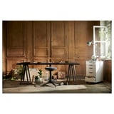 LAGKAPTEN desk: minimalist, wood, black legs, padded grey seat, white storage, wooden wall, bright window, plants.