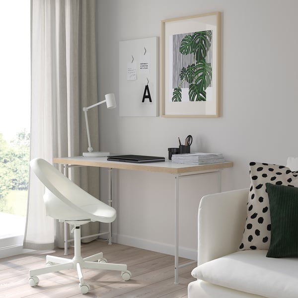 Minimalist home office with LAGKAPTEN desk, white chair, and plants poster. Desk has square pattern top, small relative to chair and sofa.