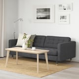 Modern living room with grey sofa, wood coffee table, floor lamp, and nature wall art.