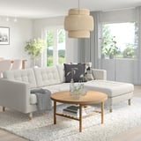 Modern living room: gray landskröna l-shaped sofa, natural wood coffee table, floral cushions, hanging textured lamp, large windows, indoor plants.