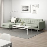 Modern living room with green sectional sofa, white coffee table, grey rug, and black-and-white art.