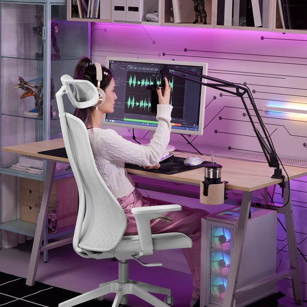 Woman using LÅNESPELARE mic arm at cluttered desk, editing audio.