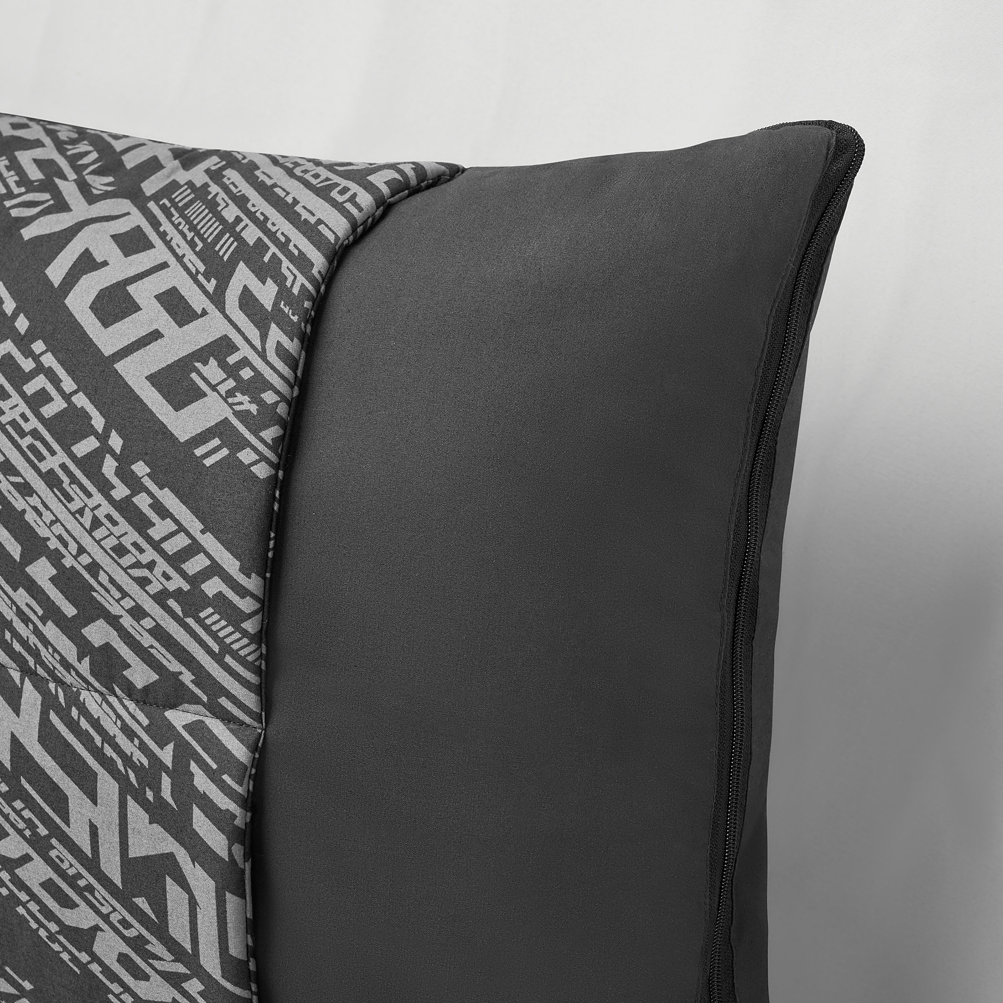A transforming cushion with a geometric pattern, shown folded with a smooth, soft texture and sturdy zipper.