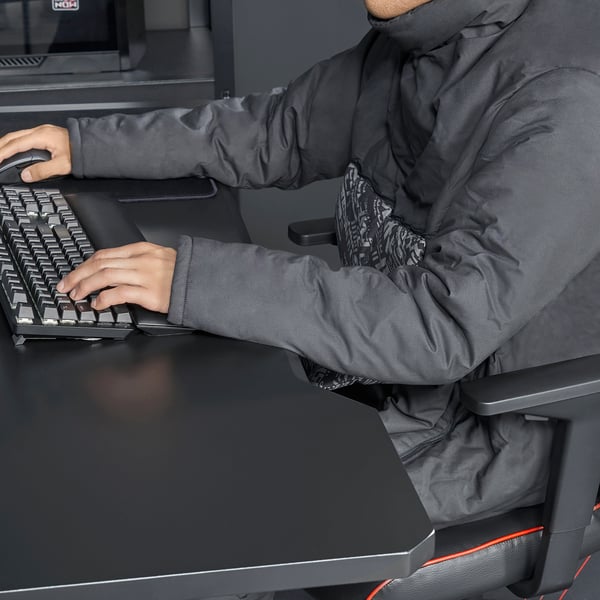 Person sitting, typing on keyboard, wearing a convertible blanket-sweatshirt.