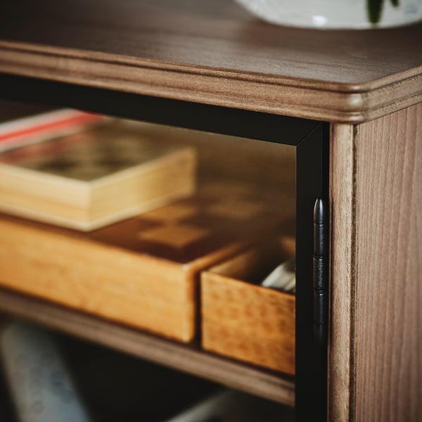 Dark wood tv stand with open drawer, books inside, and a glass door. Smart, organized design.
