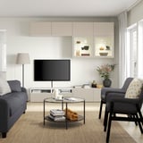 Living room with LAPPVIKEN beige cabinets, gray couch and armchair, glass coffee table, flat screen tv, and floor lamp.