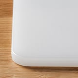 Close-up of a clean, white, textured plastic chopping board on a wooden surface, showing its smooth, even, and durable quality.