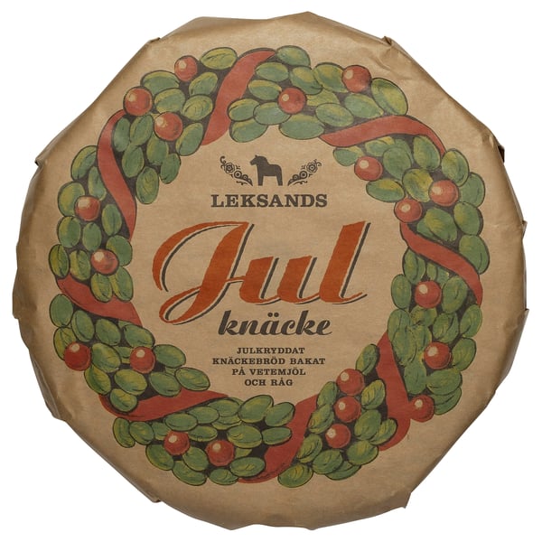 A festive wreath with berries decorates this round, LEKSANDS KNÄCKEBRÖD packaging, a traditional swedish food item.
