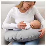 Woman in white shirt sits on couch with baby and gray nursing pillow.