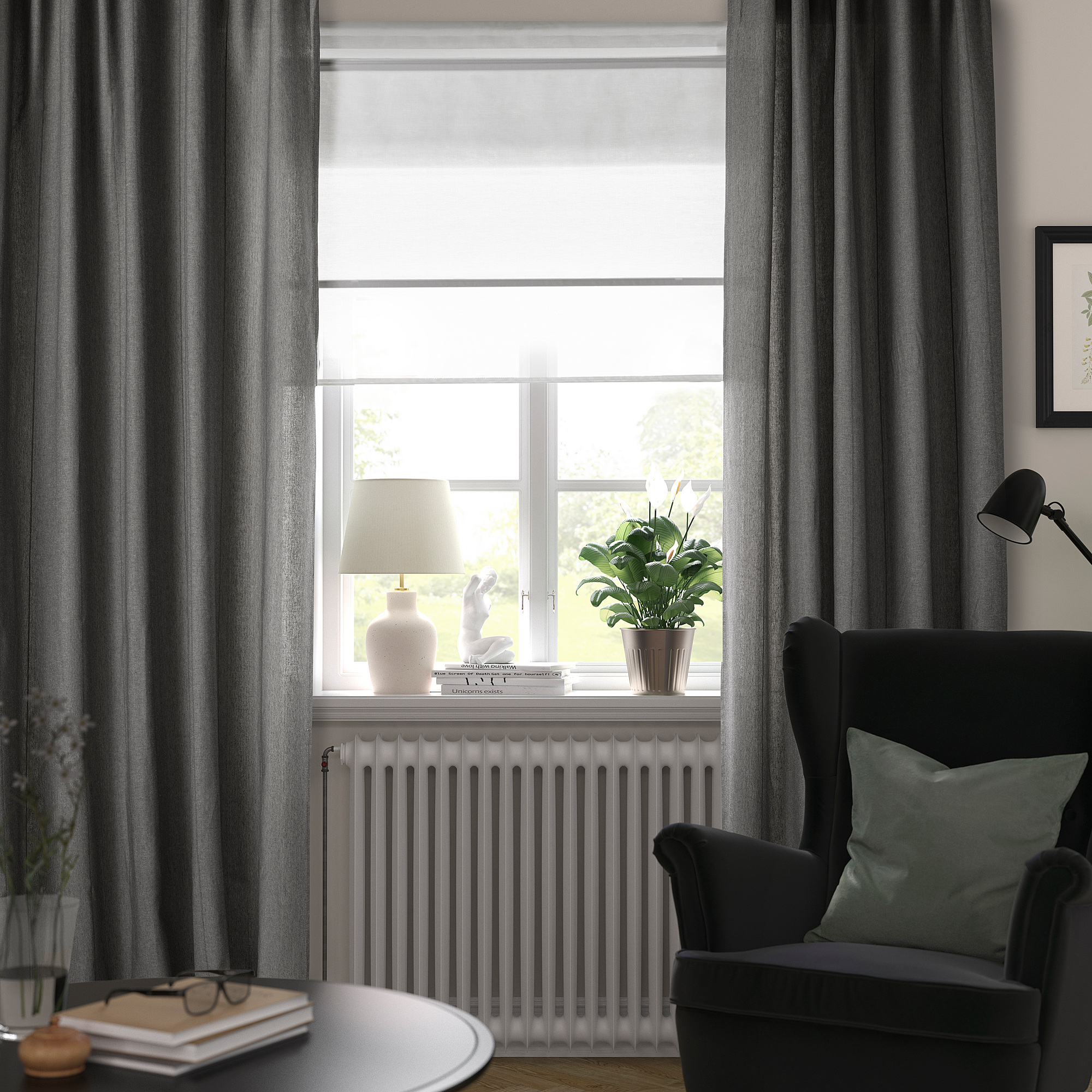 Modern room with LENDA dark grey curtains framing a large window. Curtains are drawn to show seating area with a chair, cushions, lamp, and plants.