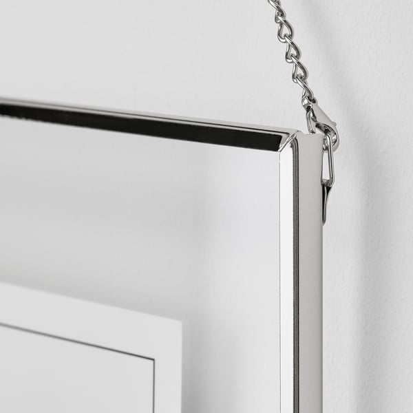 A sleek photo frame, likely LERBODA, hangs securely against a wall, showcasing a modern design with a shiny, nickel-plated chain.
