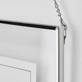 A sleek photo frame, likely LERBODA, hangs securely against a wall, showcasing a modern design with a shiny, nickel-plated chain.