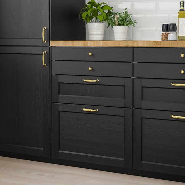 Black LERHYTTAN cabinets with gold handles, large potted plants.
