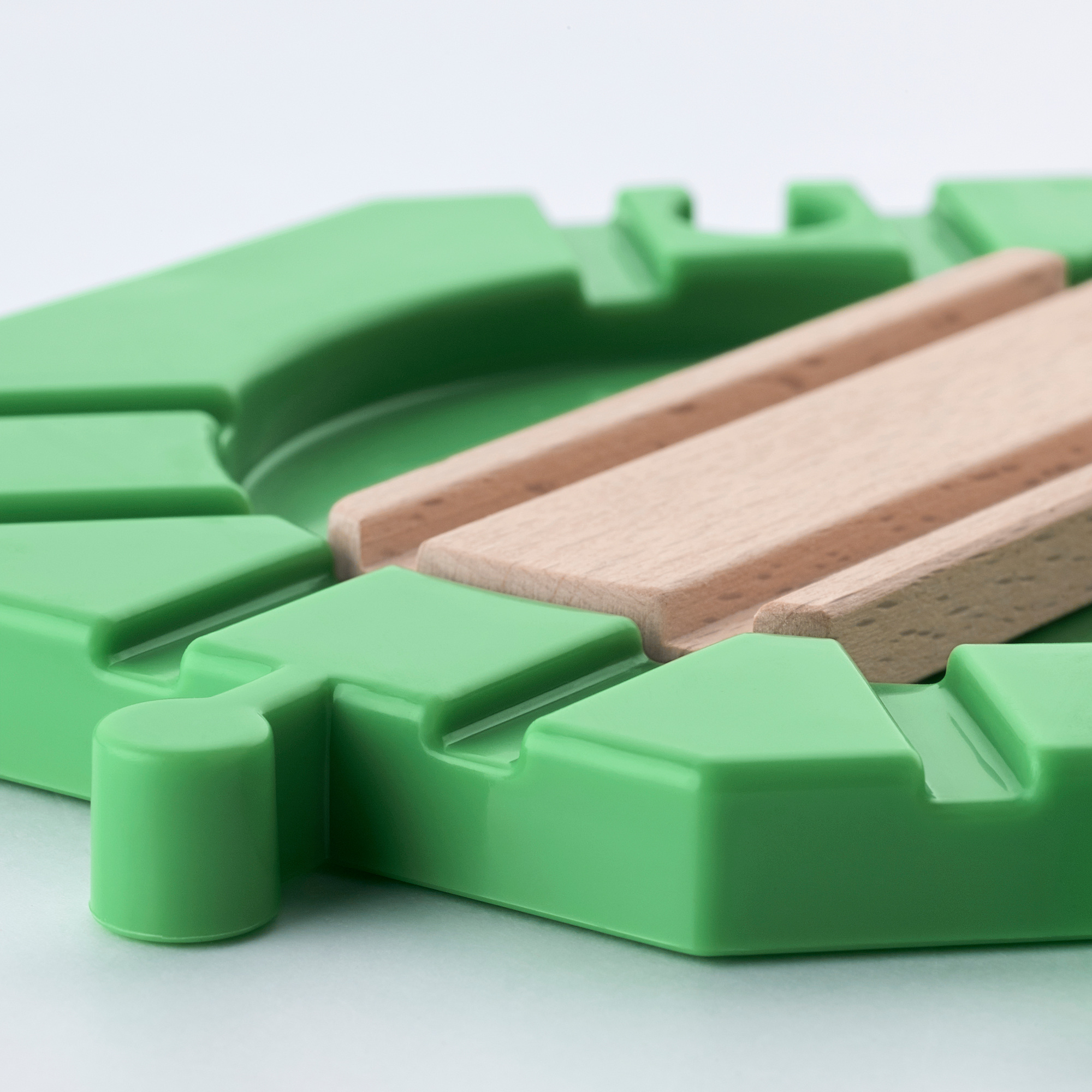 Green lego-like train track pieces & wooden plank; high-quality, interlocking design.