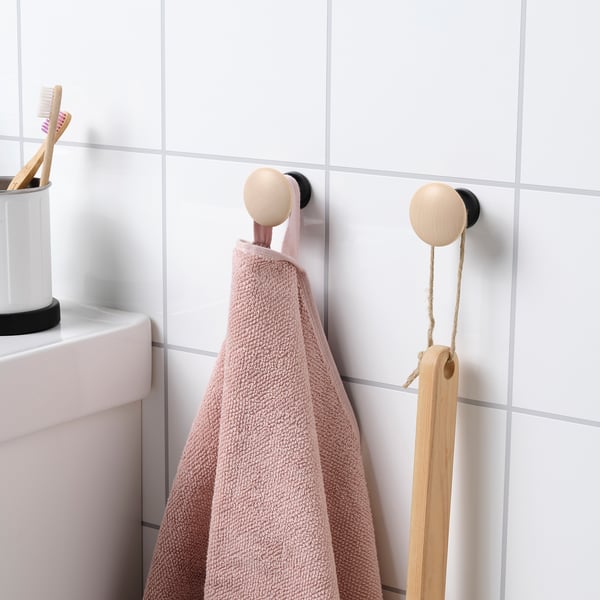 Bathroom hooks with concealed fittings holding pink towel and wooden brush.