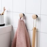Bathroom hooks with concealed fittings holding pink towel and wooden brush.