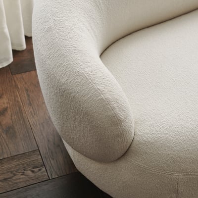 Close-up of plush, cream-colored sofa arm, showcasing soft, luxurious upholstery and elegant design.