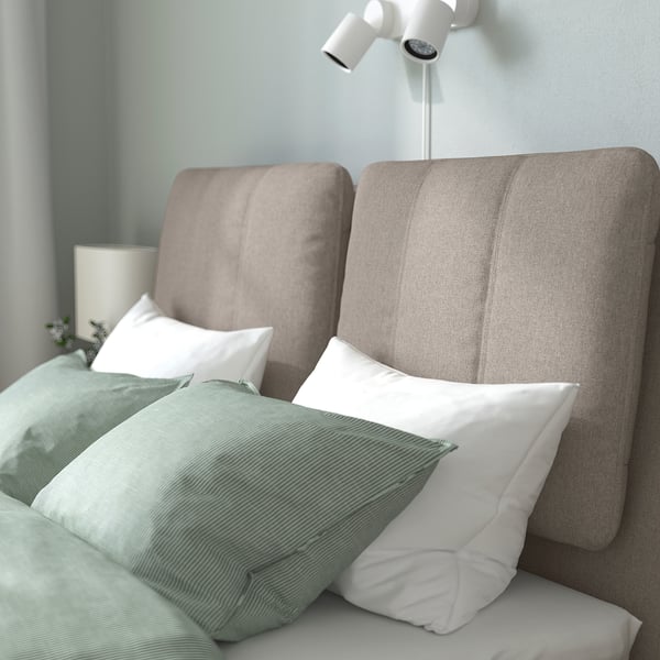 Modern bed with sloped headboard, cushions, white lights, and green bedding.