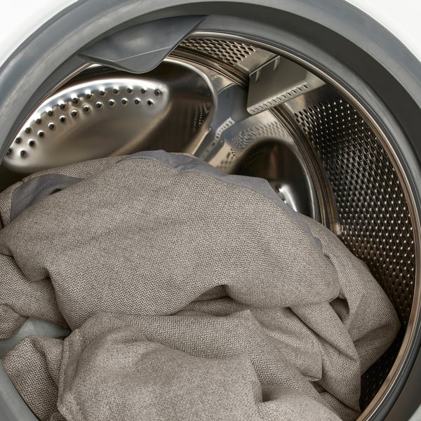Washing machine drum with gray clothes, perforated metal design.