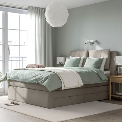 Grey LILLFJÄLLET bed with cushioned headboard, mint linens, large window, and pendant light. Spacious with storage drawers.