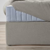 Gray upholstered bed with cushioned headboard and under-bed storage.