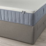 Corner view of a LILLFJÄLLET divan bed with blue ikea tag, displaying integrated storage and washable covers.