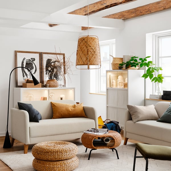 Cozy living room with light-colored furniture, including a beige 2-seat sofa, wicker pendant lamp, and natural decor elements.