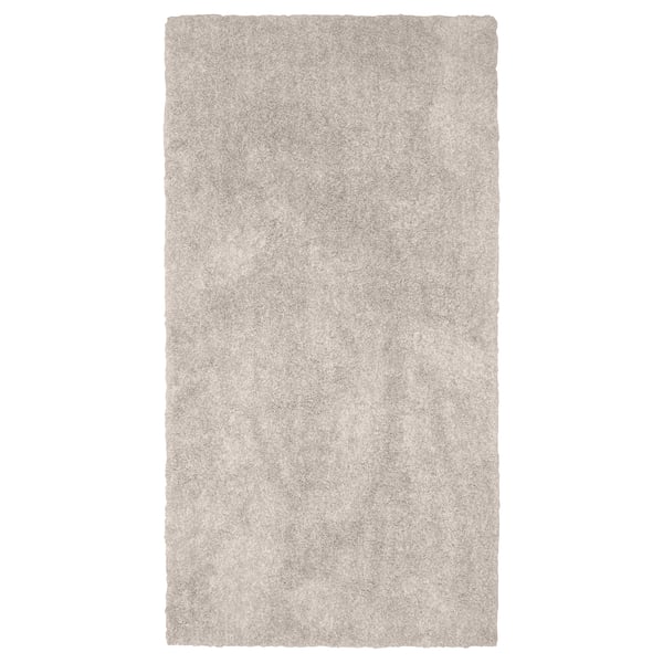 A rectangular, beige LINDKNUD rug. Made from recycled polyester, it has a soft, plush surface ideal for bedrooms.