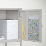 Organized white cabinet with open door revealing storage for papers, books, and other items, with label memories visible.
