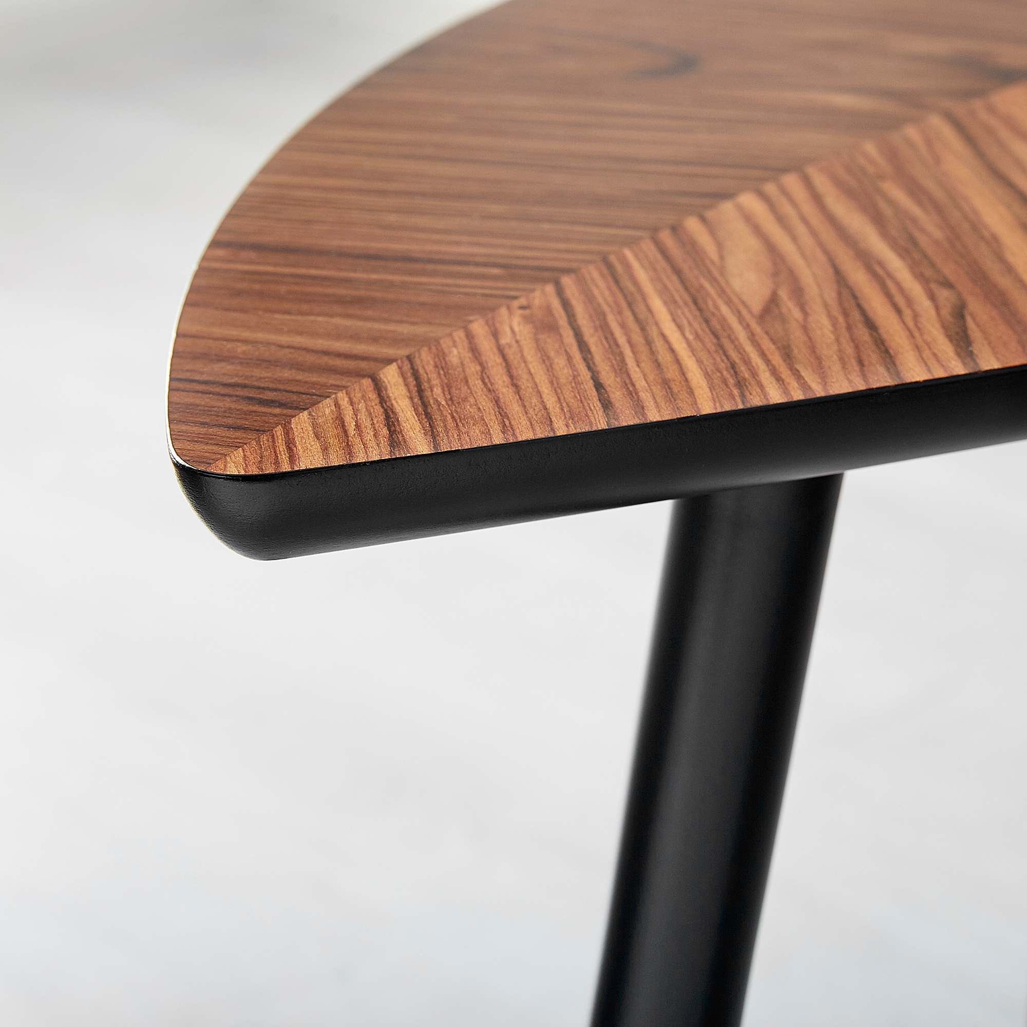 Close-up of modern wood table edge, smooth finish, black leg.